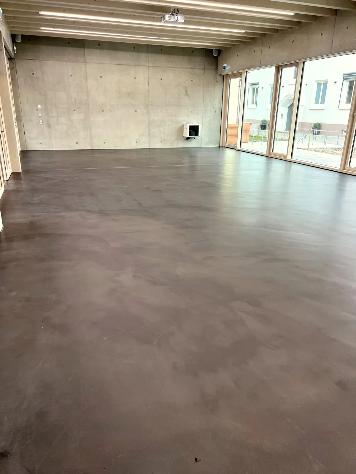 Fugenloser Designboden in einem Neubau mit Sichtbetonwand